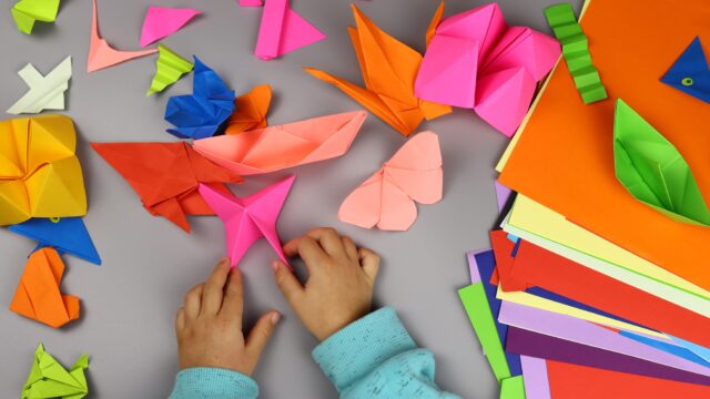 child makes origami crafts from colored paper